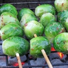 several green peppers cooking on a grill with wooden skewers sticking out of them