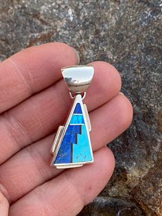 This beautifully well crafted Triangle Pendant has been handmade by a Navajo Artisan. The Colors of the Pendant come from Lapis Lazuli, Turquoise and Blue Opal. The Pendant measures 1.5” long and 5/8” wide. There are several pendants available and they will vary in color. “Winds of Wisdom” (Lapis Lazuli, Turquoise and Blue Opal. The Navajo (Dine’) believe that the wind is a powerful source. The native tradition believes that at any moment, the blowing wind can inspire one with hope, resolve, and Triangle Pendant, Blue Opal, Turquoise Blue, The Wind, Lapis Lazuli, Opal, Enamel Pins, Turquoise, Pendant