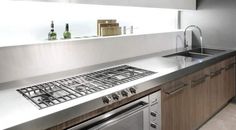 a modern kitchen with stainless steel appliances and wood cabinets, along with white countertops