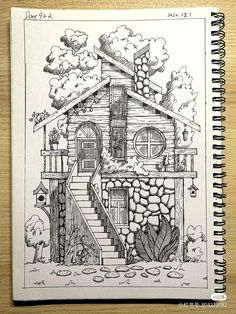 a drawing of a house on top of a wooden table next to a spiral notebook