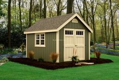 a small shed in the middle of a yard with flowers and trees around it,