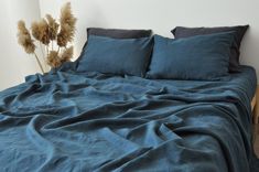 an unmade bed with blue sheets and pillows