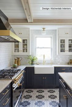 a kitchen with blue cabinets and white counter tops, gold pulls on the faucet