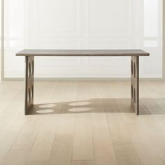 a wooden table sitting on top of a hard wood floor next to a white wall