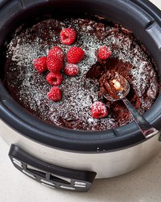 a crock pot filled with chocolate cake and raspberries