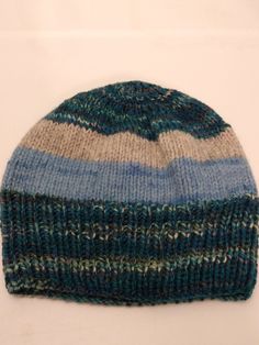 "This unique hat was hand knit on a circular needle and has no seams. It was knit from a variety of 3 beautiful yarns, The multi color blue is handyed merino from Wyoming, and has blues, greens and natural in the fabric. The semi solid light blue is Malabrigo merino wool from Uruguay, and the light gray is a natural double strand from New Zealand wool. This hat is Mediumweight and will work for all men, women and teens. It is a one size fits most, measuring 8.5\" tall and will stretch from 16-24\" across the bottom ribbed edge. These hats work for most blustery occasions, such as : hiking, climbing, camping, sleeping, shopping, fishing, jogging, walking, etc.  As with all fine fibers, this one should be hand washed and laid flat to dry. DO NOT WRING.   Purchase any two or more items from t Handmade Blue Beanie, One Size, Handmade Blue Beanie One Size, Blue Handmade Beanie One Size, Handmade Blue Beanie One Size Fits Most, Casual Blue Knitted Beanie, Blue Handmade One-size Beanie, Handmade Blue One-size Beanie, Handmade Blue Beanie Cap, Blue Knitted Beanie Cap