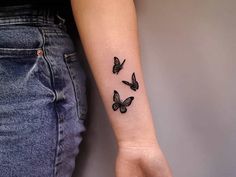 a woman's arm with three small butterflies on the left side of her arm