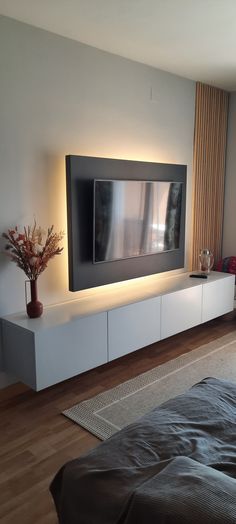 a living room with a large flat screen tv on the wall and a plant in front of it