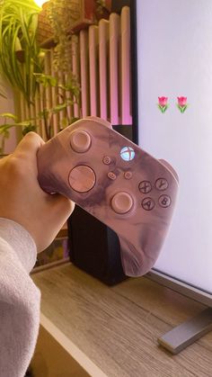 a person holding a remote control in front of a screen with pink flowers on it