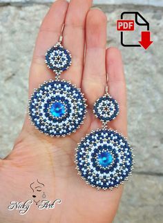 a pair of blue and white beaded earrings on someone's hand with an arrow pointing to it