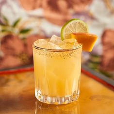 a close up of a drink on a table with a slice of orange and lime