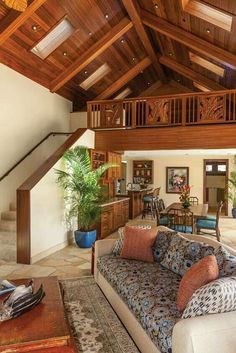 a living room filled with furniture next to a stair case and wooden ceiling above an open floor plan