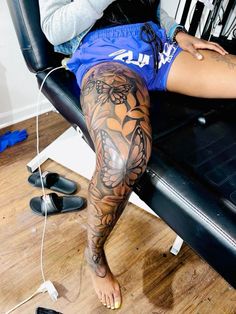 a woman sitting in a chair with tattoos on her legs