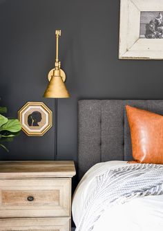 a bed room with a neatly made bed next to a night stand and two framed pictures on the wall