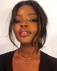 a close up of a woman wearing a necklace and black shirt with gold chains on her neck