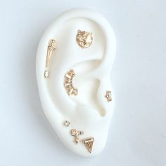 a white ear with several different types of earrings on it's side, sitting on top of a white surface