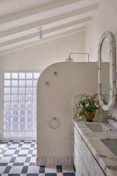 a bathroom with a checkered floor and white walls, along with an oval shaped shower