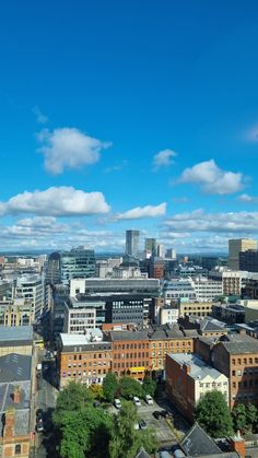 the city is full of tall buildings under a blue sky with white clouds in the background