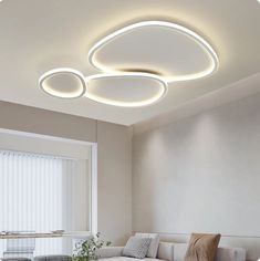 a living room with white furniture and lights on the ceiling is lit by modern lighting fixtures