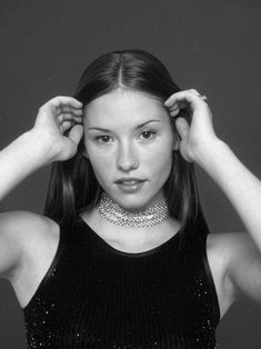 black and white photograph of a woman wearing a choker with her hands on her head