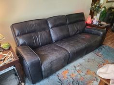 a brown leather couch sitting in a living room next to a table and lamp on top of a rug