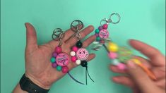 two hands holding different colored beads and key chains