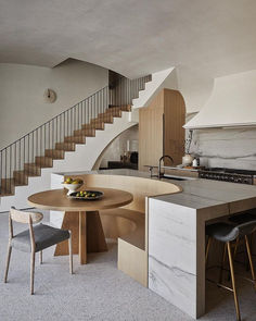 a kitchen with an island and stairs in the center, next to a dining table