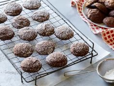 chocolate covered cookies cooling on a wire rack next to a bowl of powdered sugar