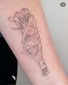 a woman's arm with a tattoo on it that has flowers wrapped in a ribbon