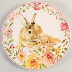 a plate with two rabbits and flowers painted on the front, sitting on a carpeted floor