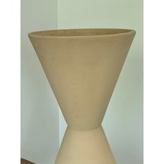 a large white vase sitting on top of a wooden table next to a planter