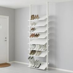 a white shoe rack with several pairs of shoes on it in the corner of a room