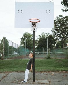 a young boy standing in front of a basketball hoop