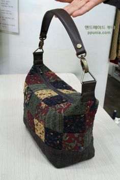 a handbag is being held by a woman's hand on a white table