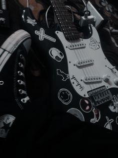 a black and white guitar sitting on top of a pair of converse shoes with skulls all over it