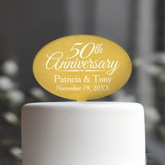 a white cake topped with a yellow 50th anniversary sign