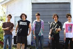 five young men standing in front of a house