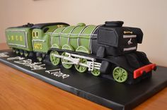 a green and black toy train sitting on top of a wooden table