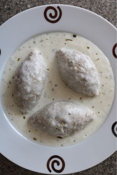 three meatballs covered in white sauce on a plate