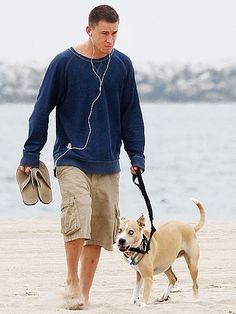 a man walking his dog on the beach with ear buds in his ears and headphones around his neck