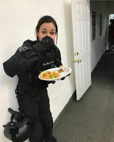 a woman in black is holding a plate with food on it while standing next to a door