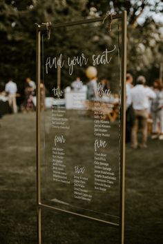 a sign that says find your seat at the end of a wedding ceremony with guests in the background