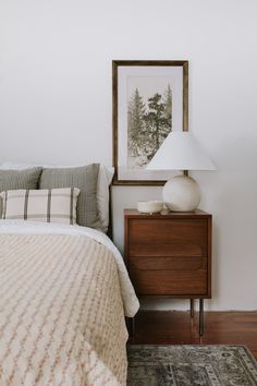 a bedroom with a bed, night stand and lamp on the nightstand next to it