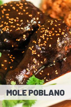 two pieces of meat on a plate with rice and cilantro