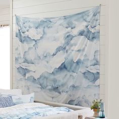 a blue and white bedroom with a large tapestry hanging on the wall