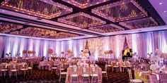 a banquet hall with tables, chairs and chandeliers on the ceiling is lit up