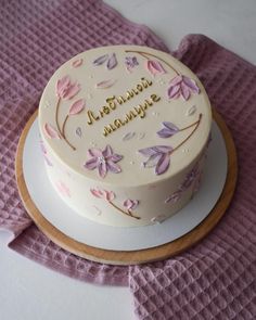 a decorated cake sitting on top of a white plate next to a pink napkin and purple cloth