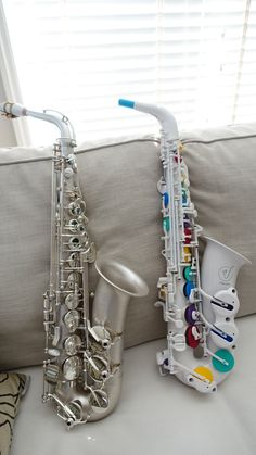 a silver saxophone sitting on top of a couch next to a window