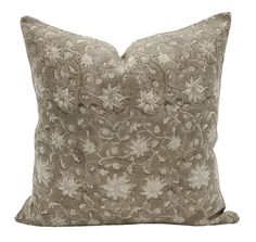 a gray and white pillow with flowers on the front, sitting on a white background