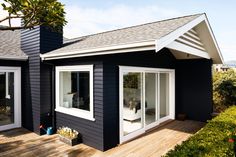 a black house with white trim and wood decking on the outside, has an open patio area